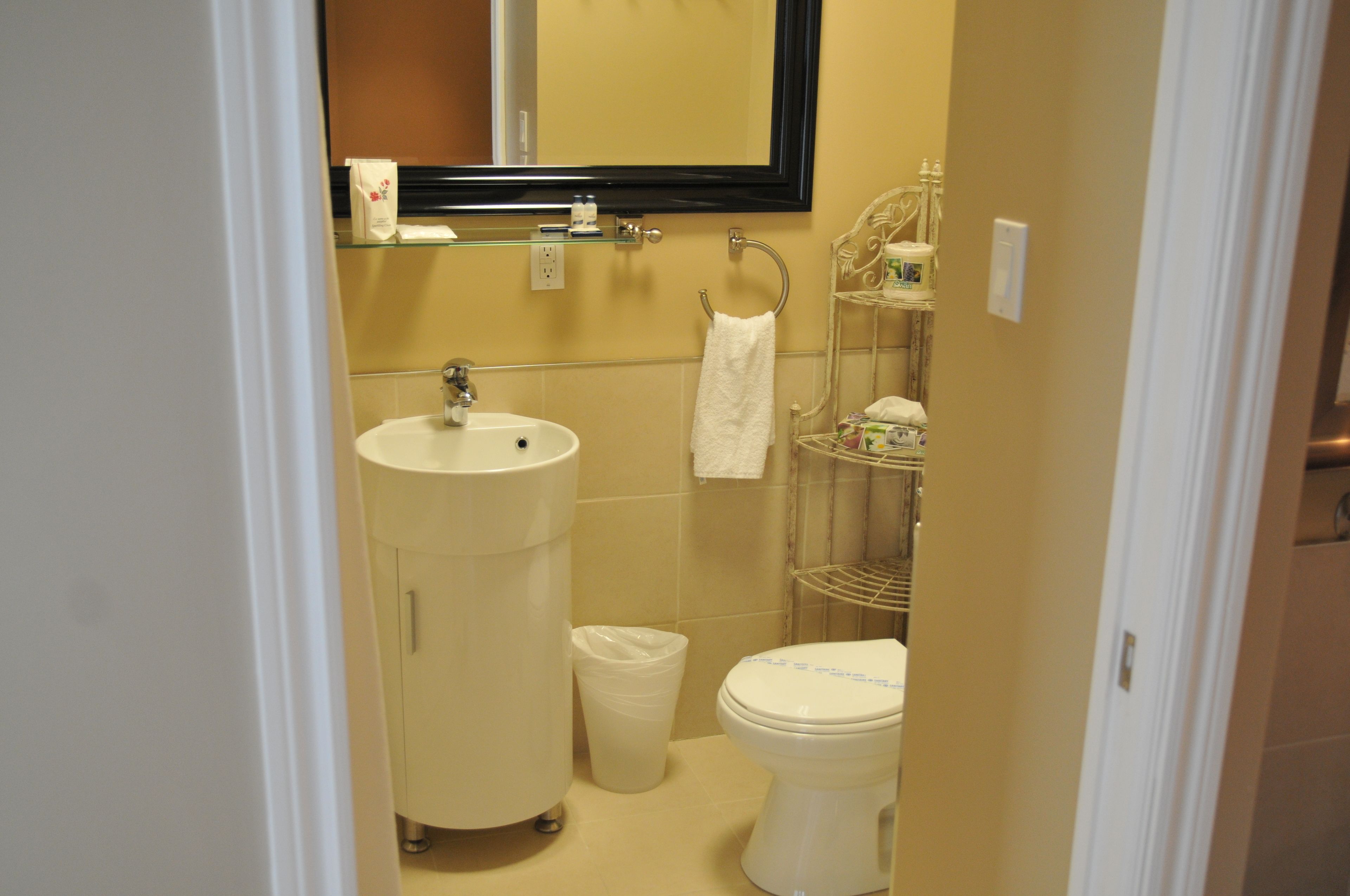 A compact bathroom with a sink, toilet, and a mirror.