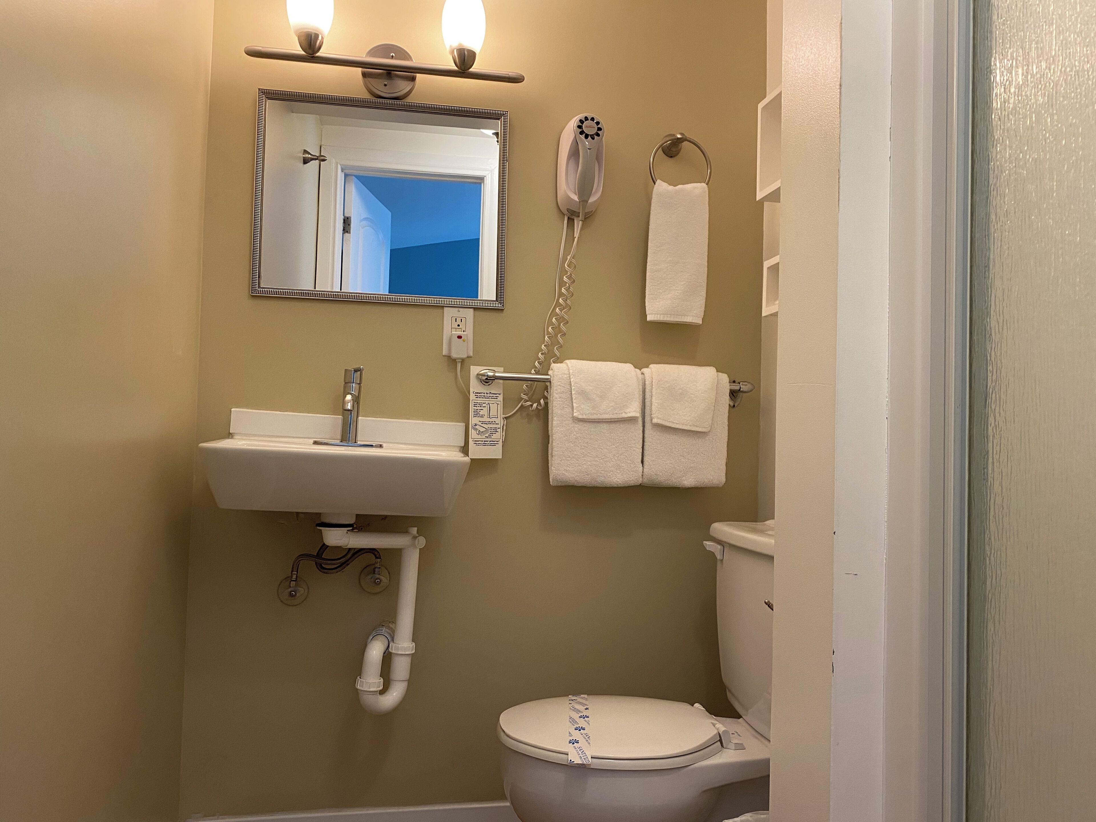A bathroom with a sink, mirror, towel rack, and toilet.
