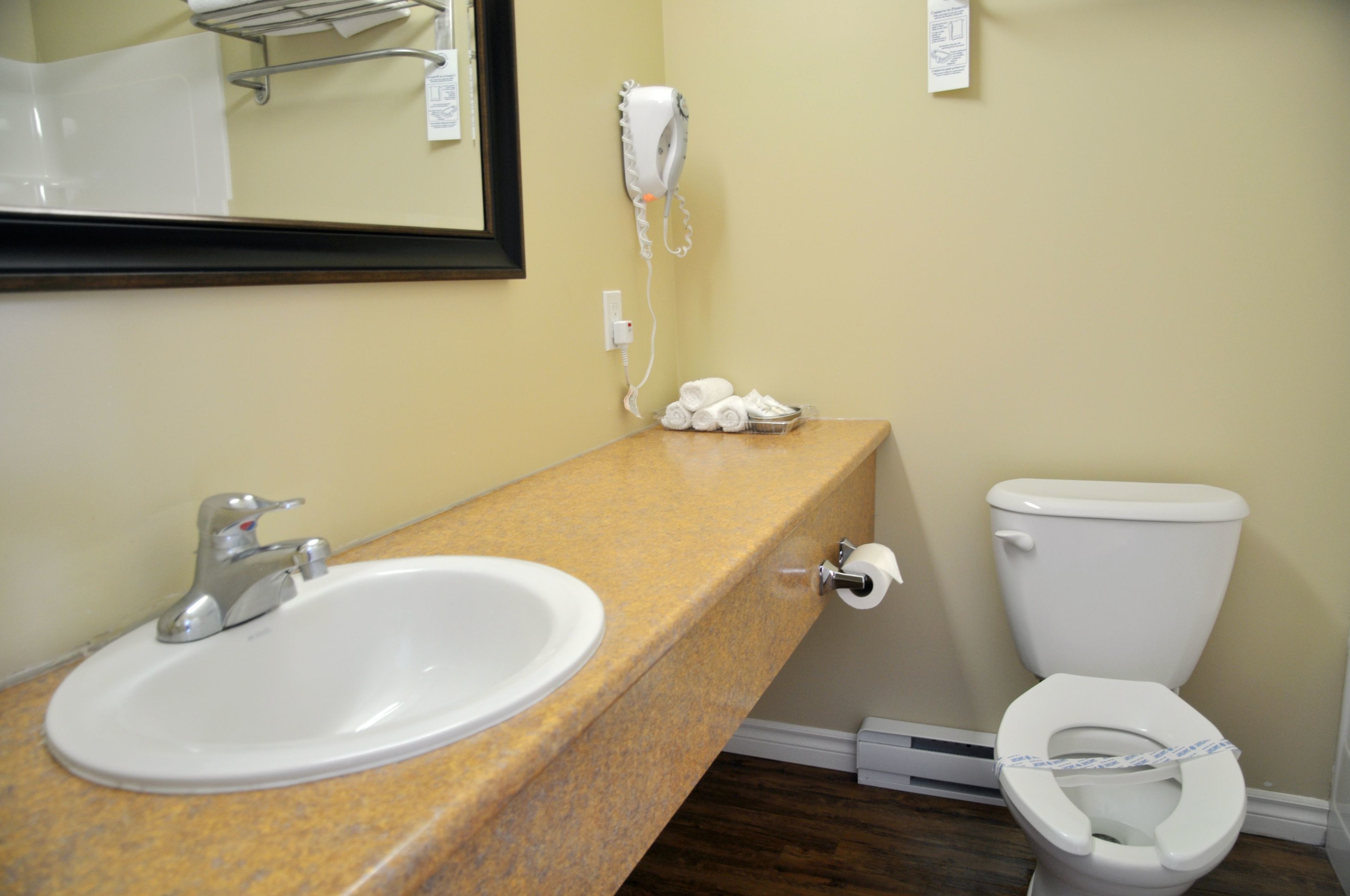 A bathroom with a sink, toilet, and a hairdryer mounted on the wall.