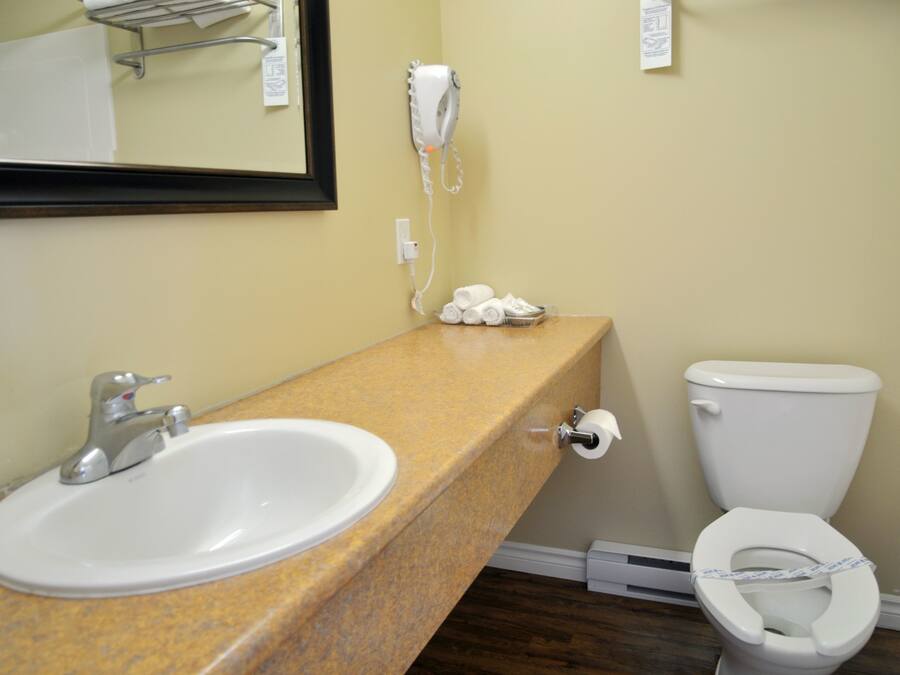 A bathroom with a sink, toilet, and a hairdryer mounted on the wall.