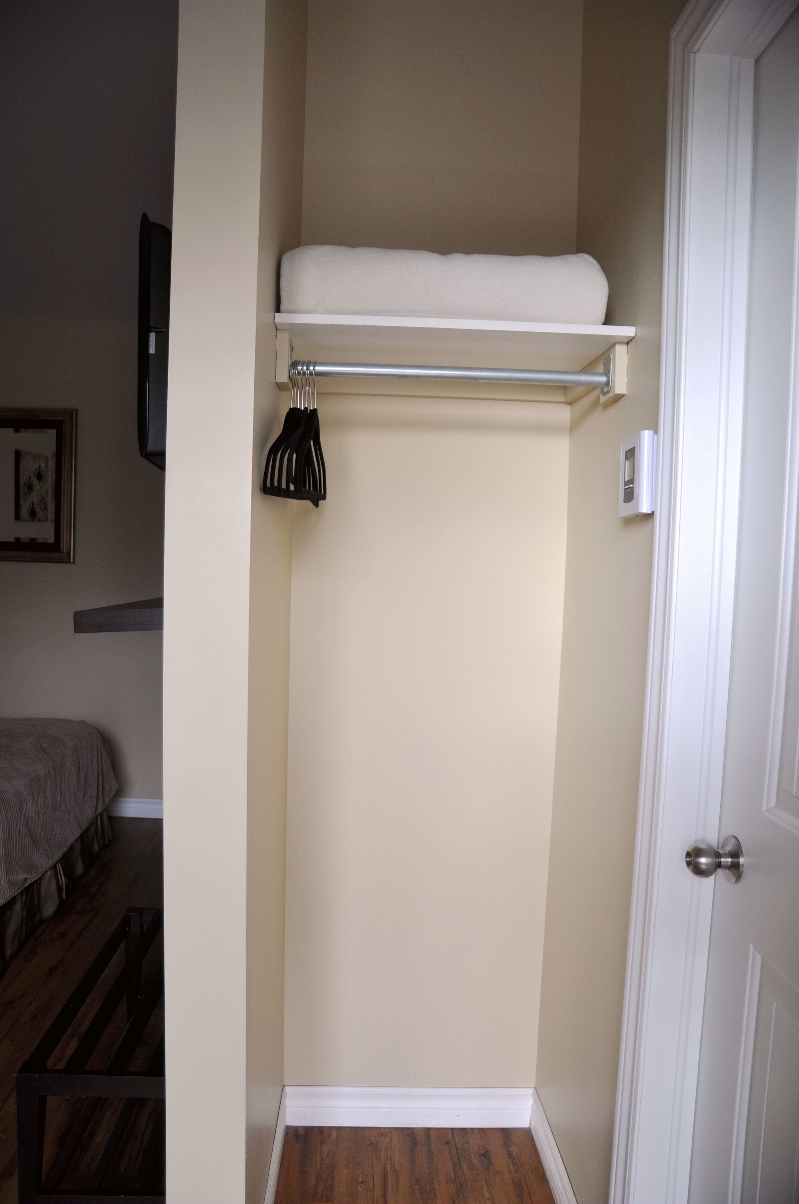A small, narrow room with a wooden floor, a white door, and a white wall.