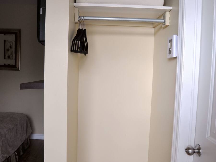 A small, narrow room with a wooden floor, a white door, and a white wall.