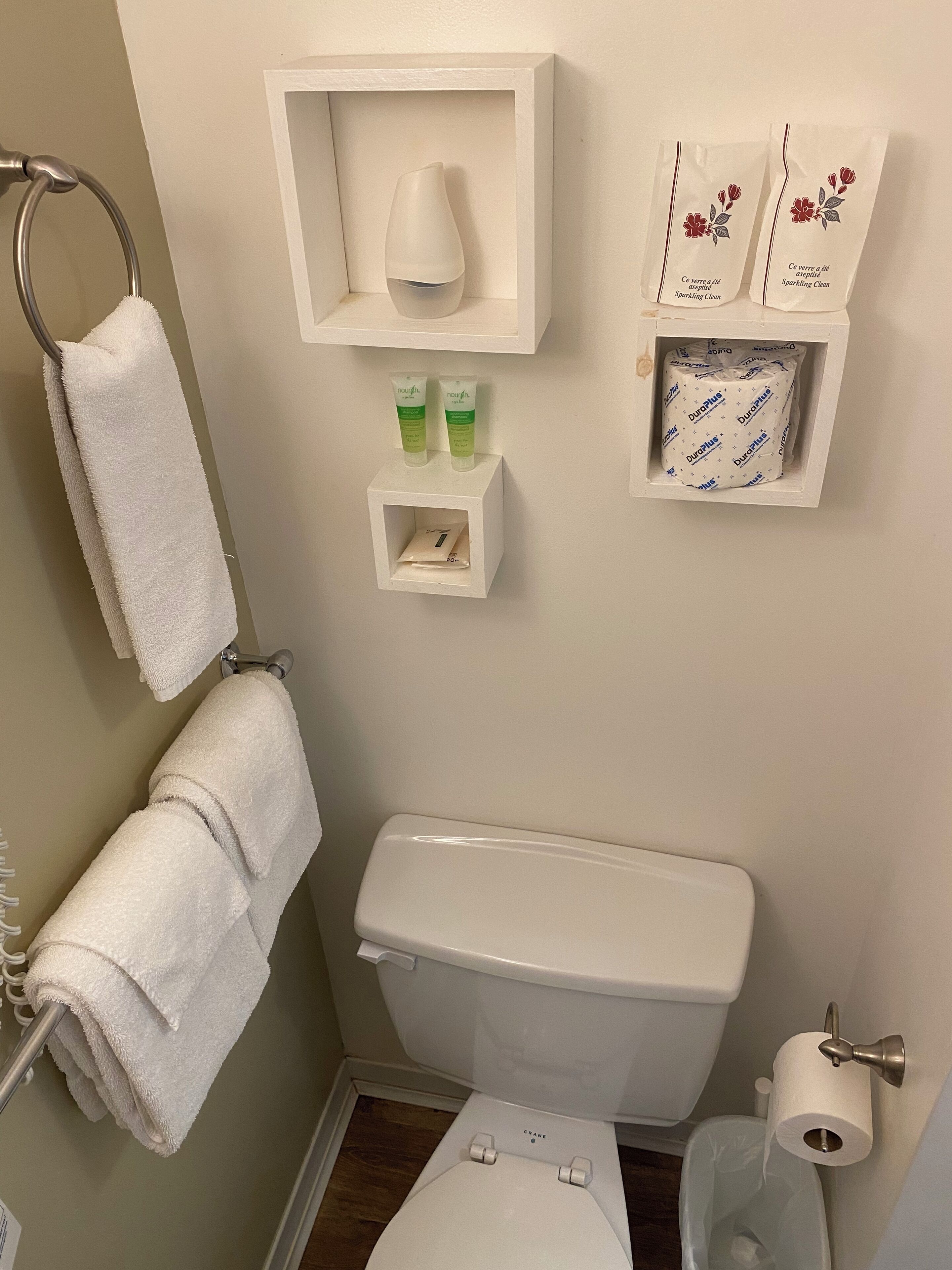 Een badkamer met een toilet, een handdoekhouder, een zeepdispenser en een toiletrolhouder.