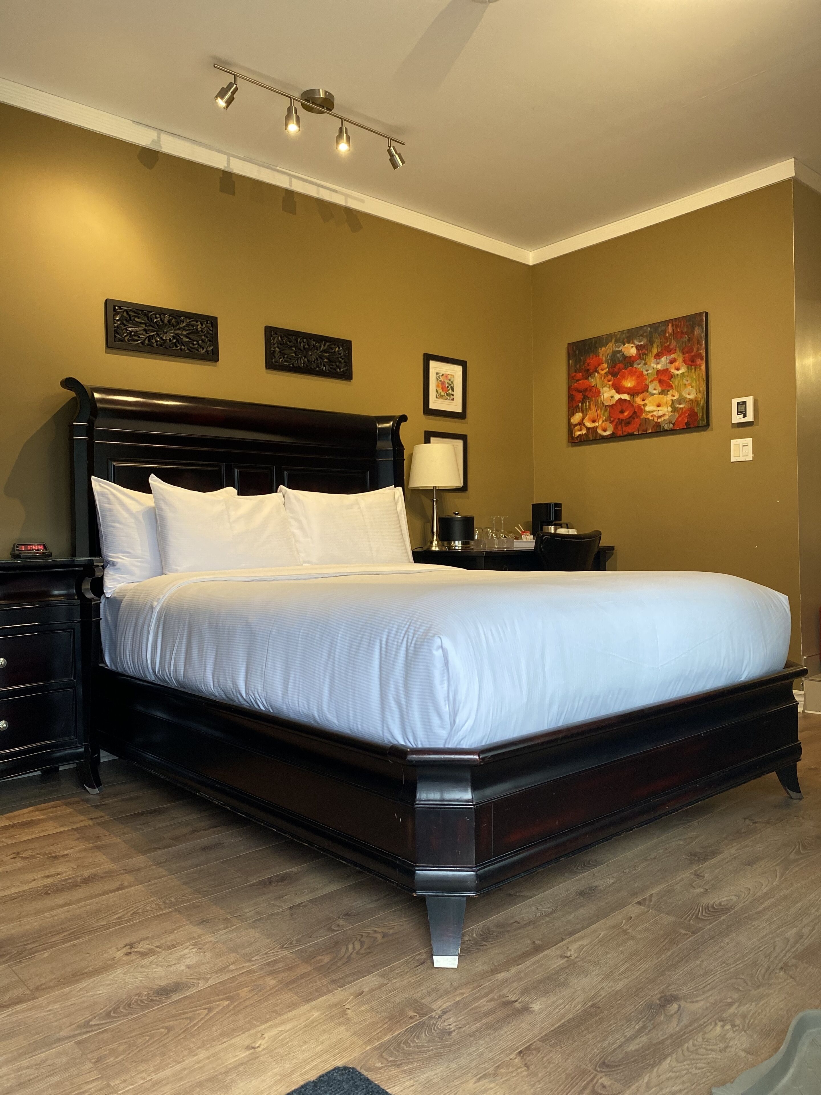 A neatly made bed with white linens, a dark wooden headboard, and a bedside table with a lamp.
