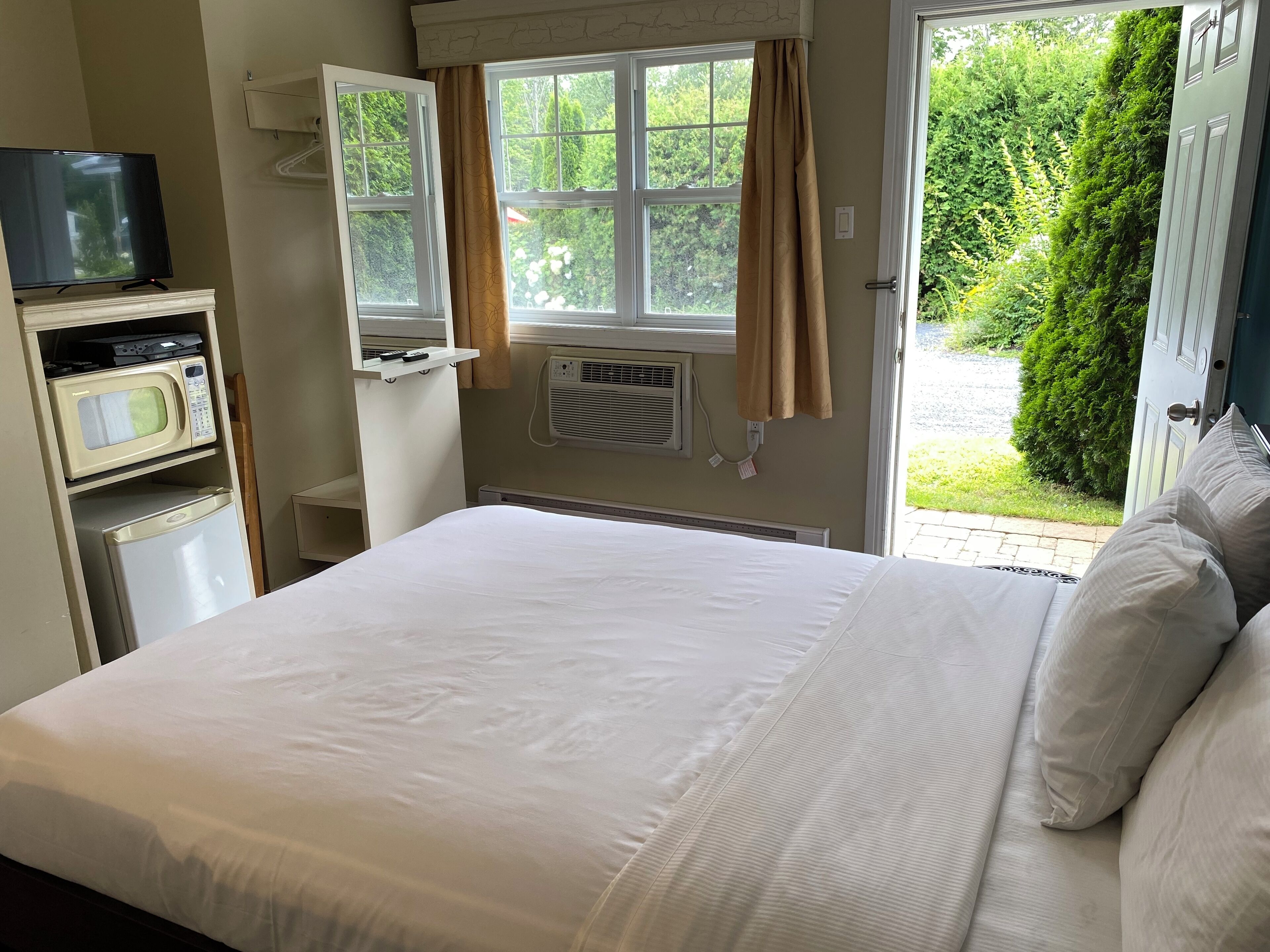 Ein Schlafzimmer mit einem Bett, einem Fernseher, einer Mikrowelle und einer Heizung.