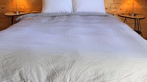 A bed with white bedding, two white pillows, and a framed mountain photograph on the wall. - Attitude Montagne (St-Adolphe-d'Howard)