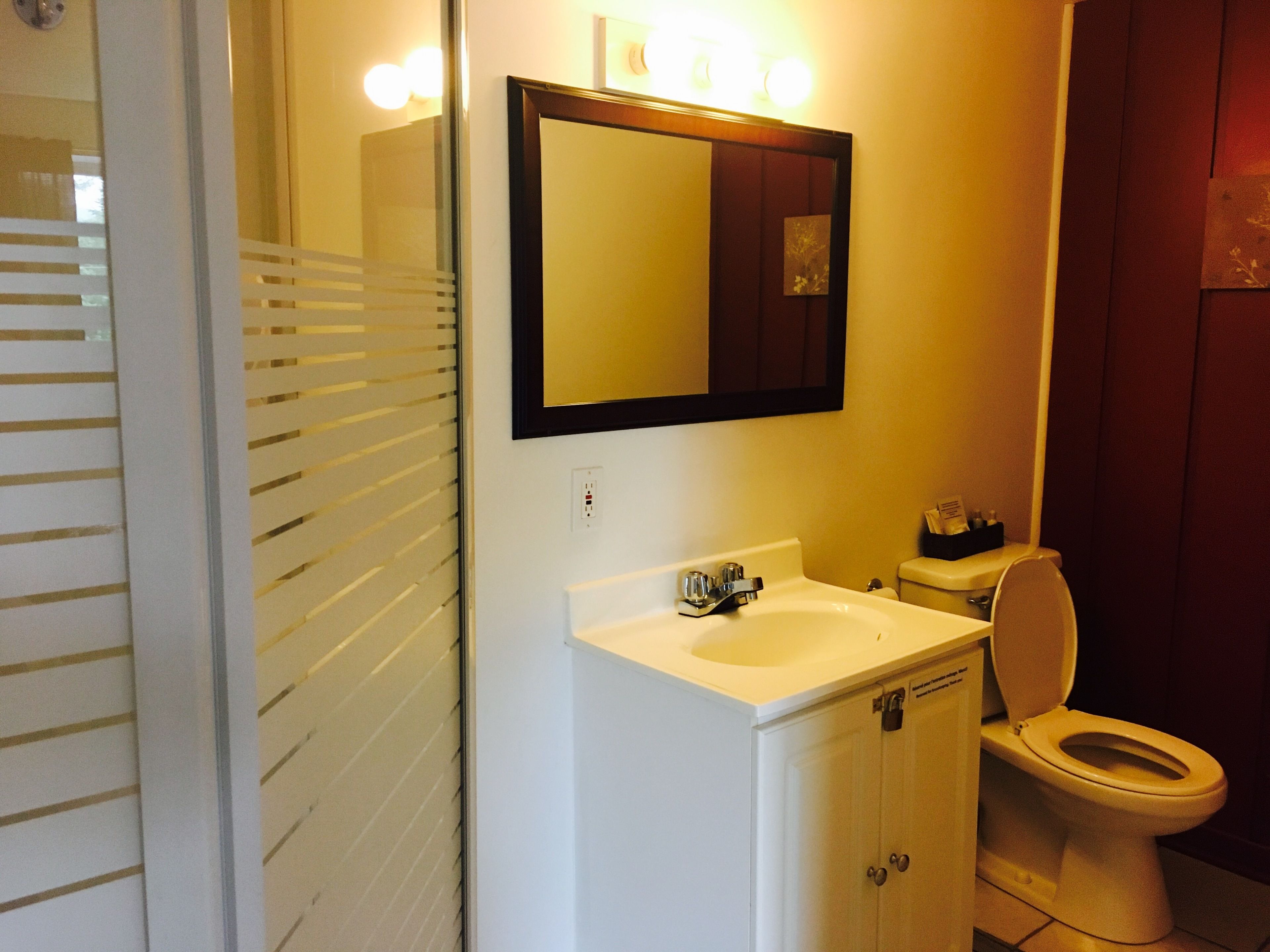 A bathroom with a white sink, a mirror above it, and a toilet.