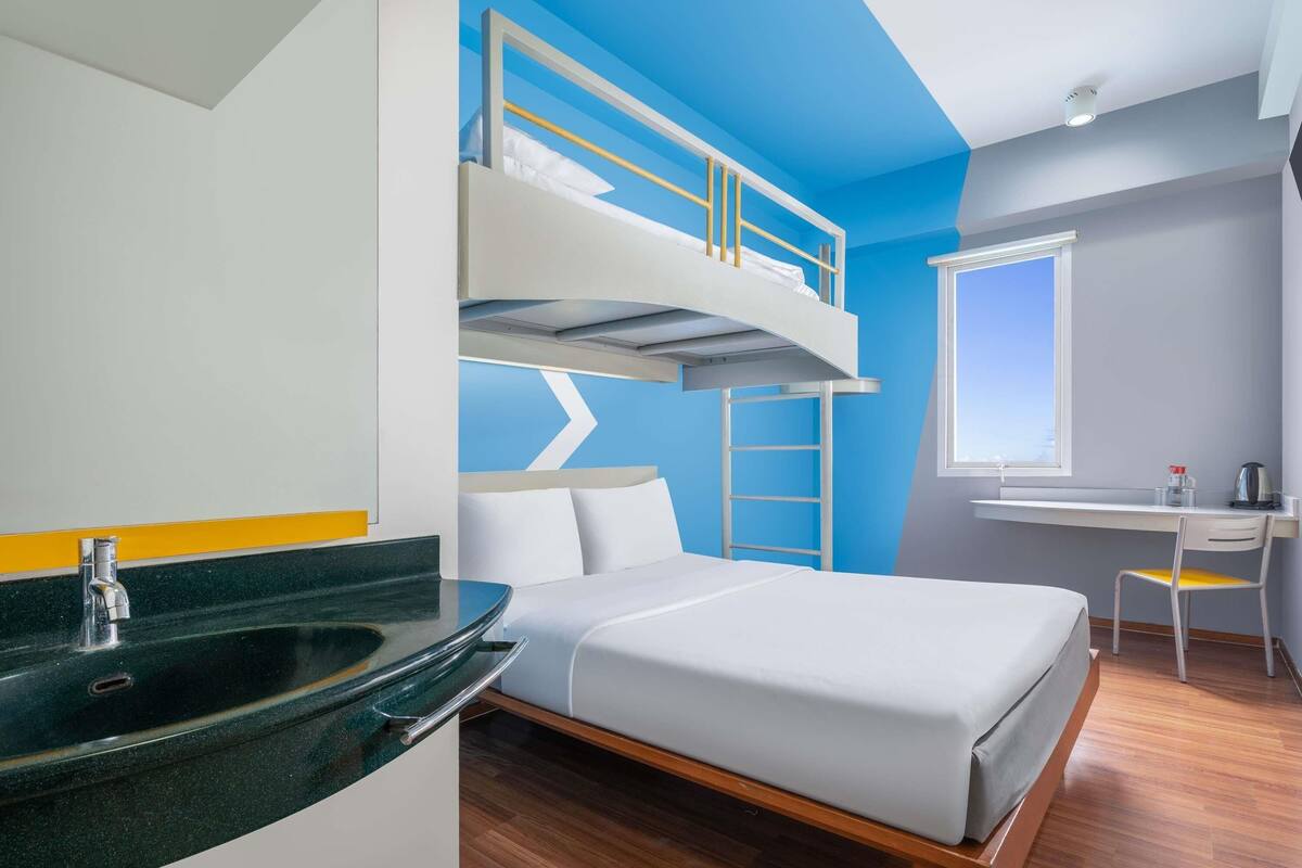 A bunk bed room with a desk and a window.