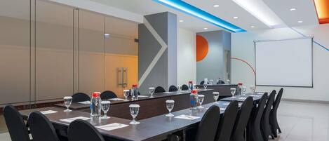 A conference room with a long table, black chairs, water bottles, and glasses.