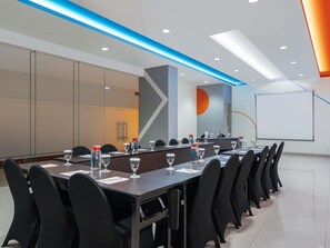 A conference room with a long table, black chairs, water bottles, and glasses.