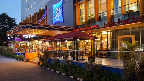 Un hotel con fachada moderna, múltiples ventanales y un cartel llamativo de 'Black Canyon Coffee'.