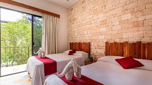 A hotel room with two beds, a brick wall, and a balcony with a view of greenery. - Hotel Casa Hipil (Valladolid)