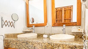 A bathroom with two sinks, wooden cabinets, a mirror, and a towel rack. - Hotel Casa Hipil (Valladolid)