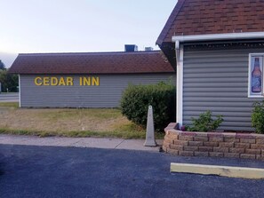 A building with a sign that reads "CEDAR INN" and a brick wall.