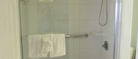 Eine gläserne Duschkabine mit Handbrause und einem Handtuchhalter mit zwei Handtüchern.