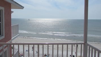 A balcony with a view of the beach and ocean.