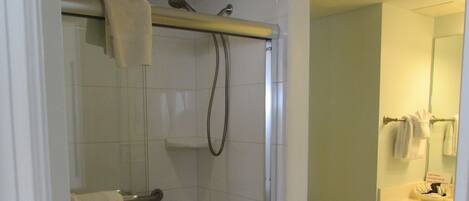 Een badkamer met een douchecabine van glas, een toilet en een wastafel met spiegel.