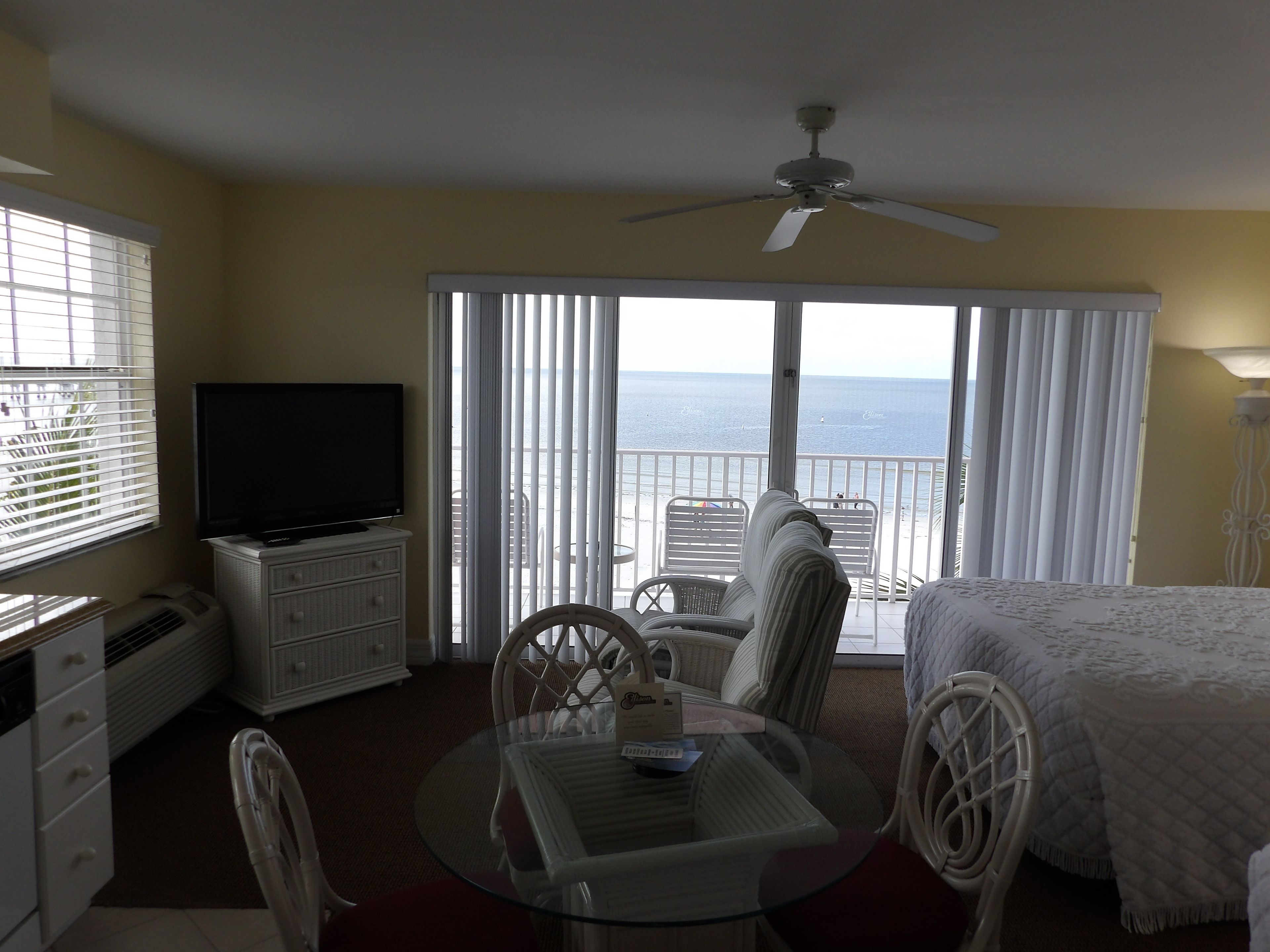 Una habitación con balcón, televisión, mesa de comedor y cama.