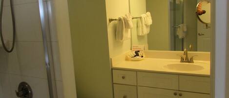 A bathroom with a shower, toilet, sink, and mirror.