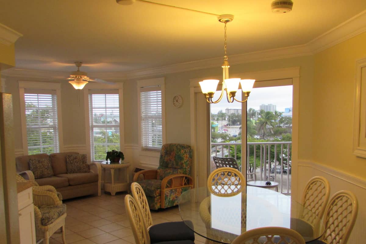 A spacious living room with a dining area, large windows, and a view of the city.