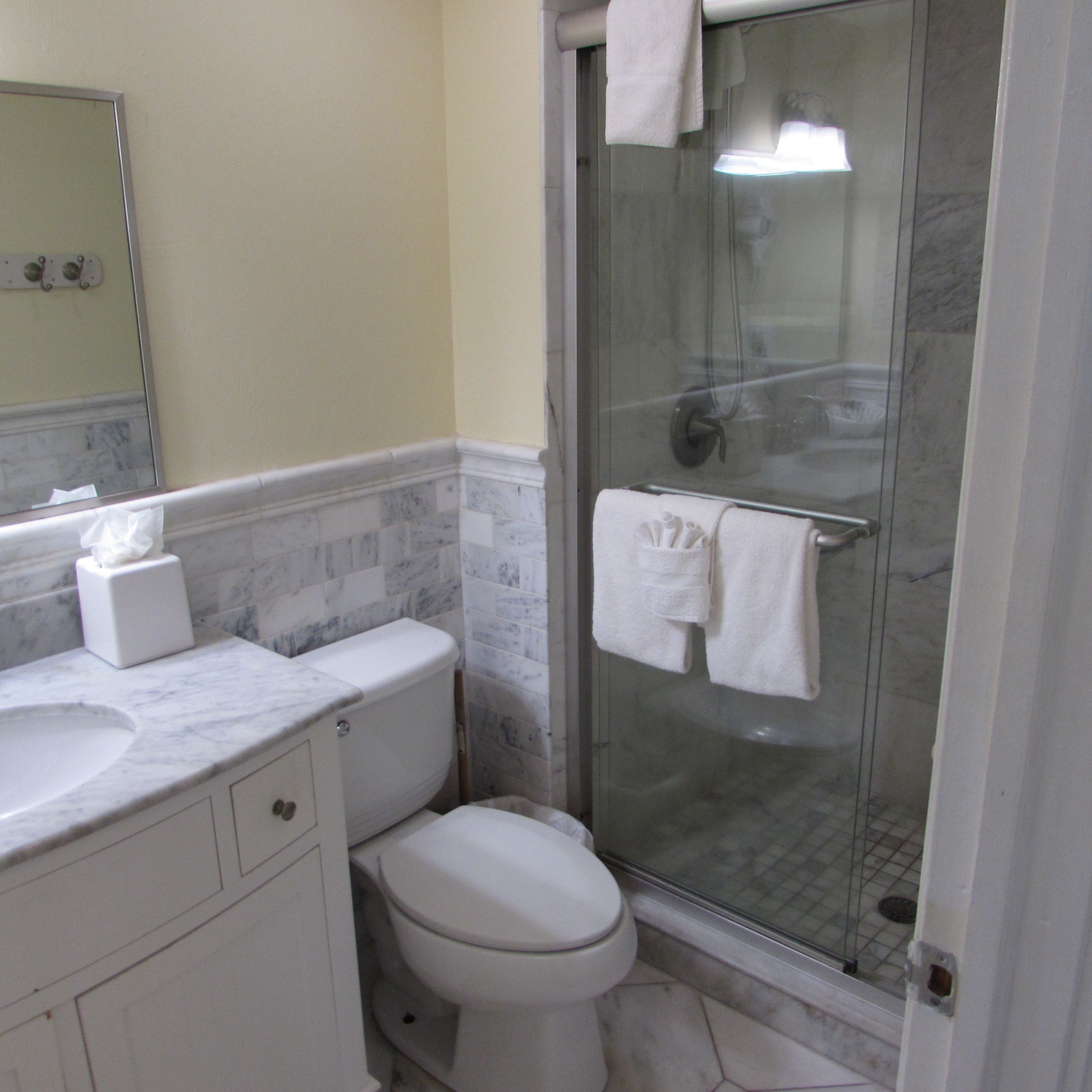 Une salle de bain avec un lavabo en marbre, des toilettes et une douche séparée par une paroi de verre.