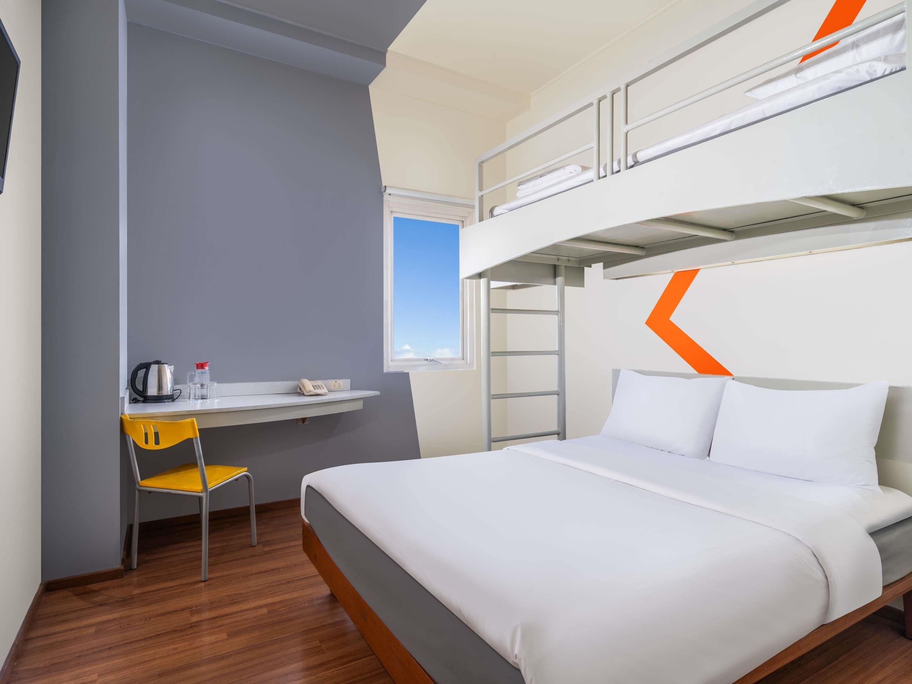 Une chambre avec un lit superposé, un bureau, une chaise et une fenêtre.
