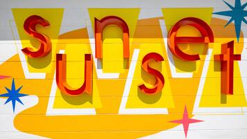 Una pared con letras grandes y coloridas que deletrean “SUNSET” y estrellas decorativas.