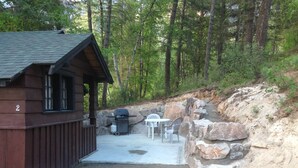 A cabin with a porch, outdoor seating, and a grill. - Addison's Bungalows (Brisco)