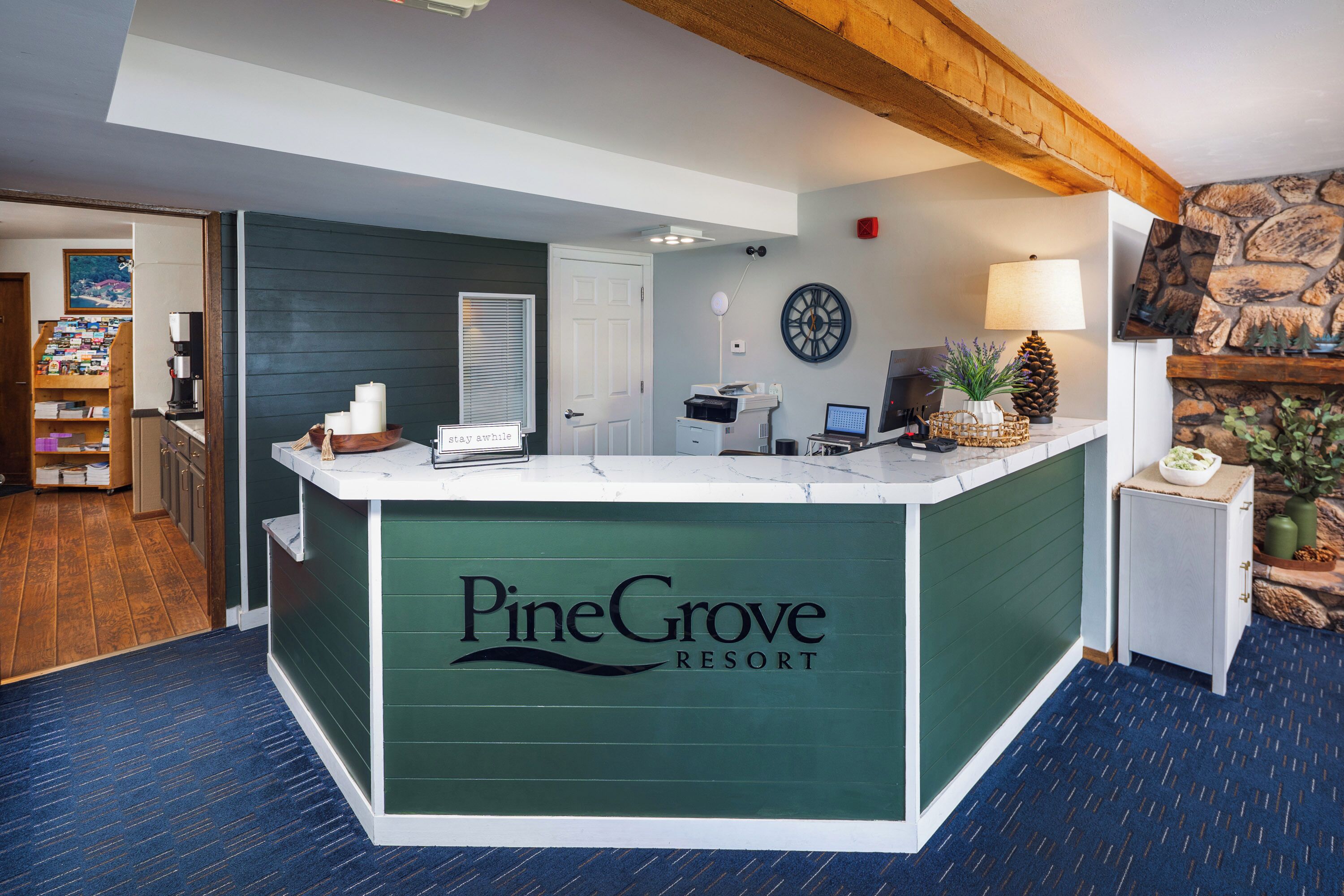 A reception desk at Pine Grove Resort with a sign, a clock, and a lamp.