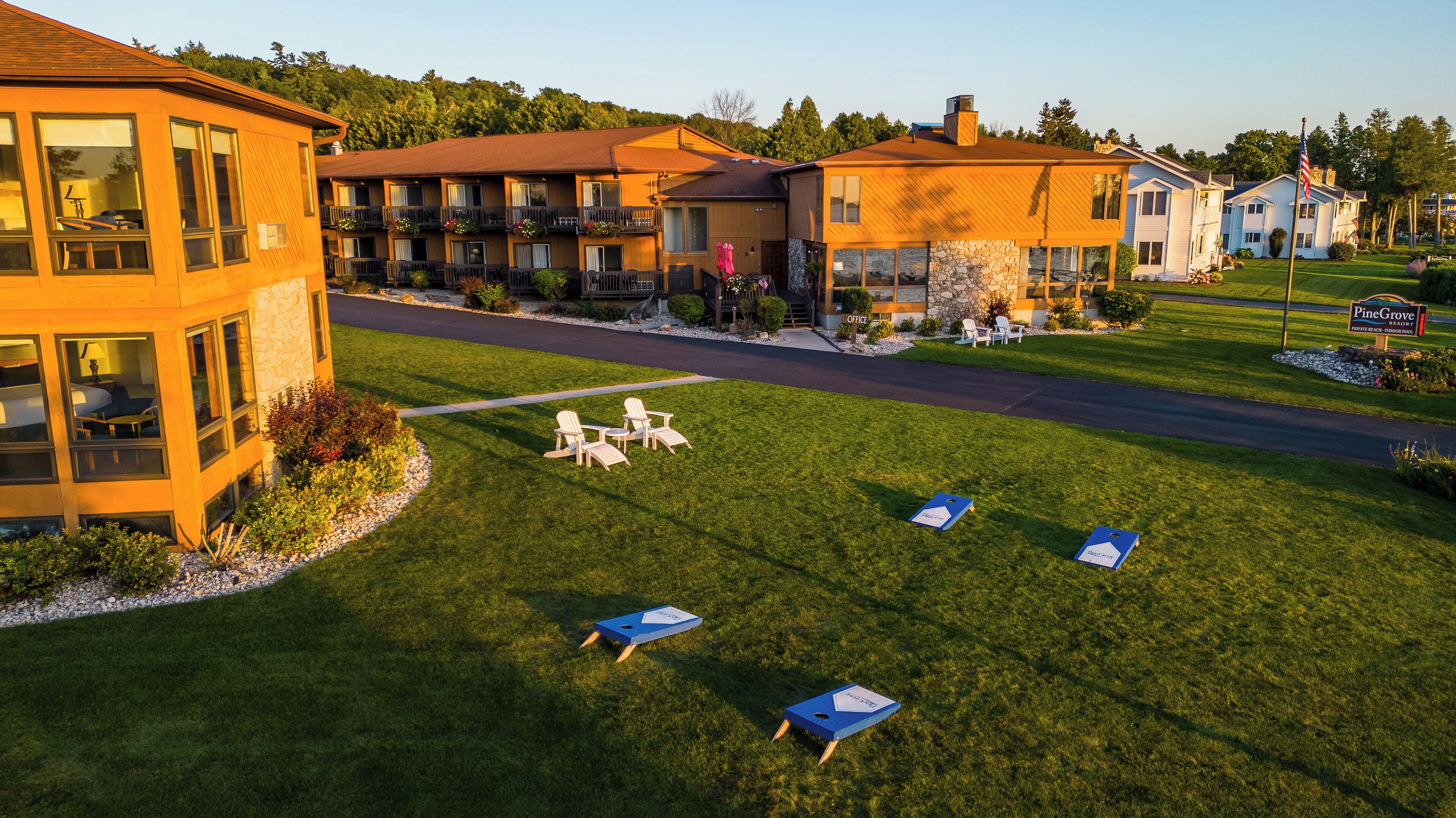 Un resort con varias edificaciones, un césped cuidado, asientos al aire libre y una bandera.