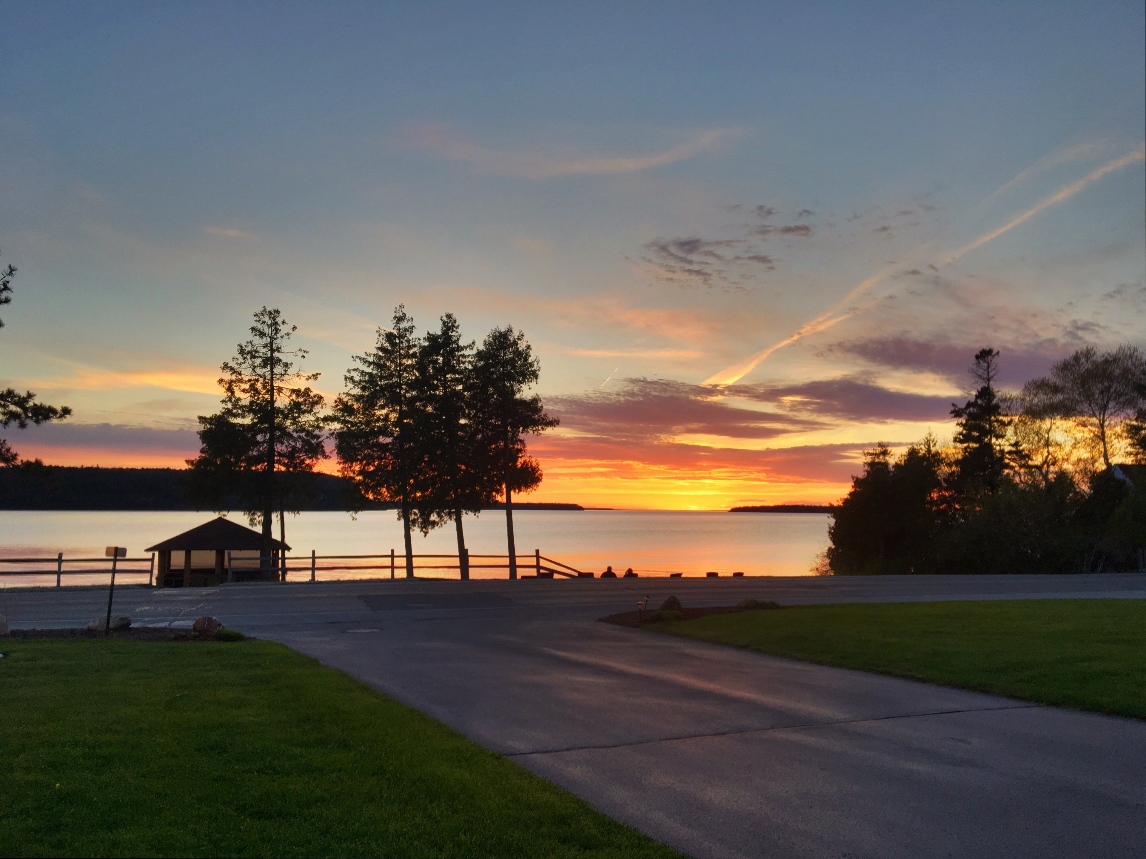 Une vue sur le lac, avec un belvédère, des arbres et un coucher de soleil.