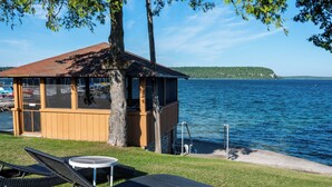A wooden structure with a roof overlooking a lake, accompanied by lounge chairs and a small table. - Pine Grove Resort (Ephraim)