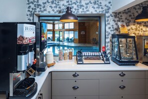 A coffee shop with a coffee machine, a waffle maker, and a pool view. - Pine Grove Resort (Ephraim)