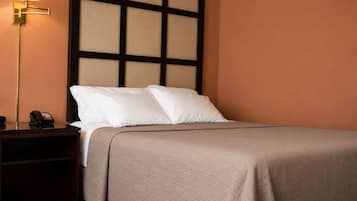 Une chambre d’hôtel avec un lit, une table de chevet avec un téléphone et un mur orné d’un motif quadrillé.