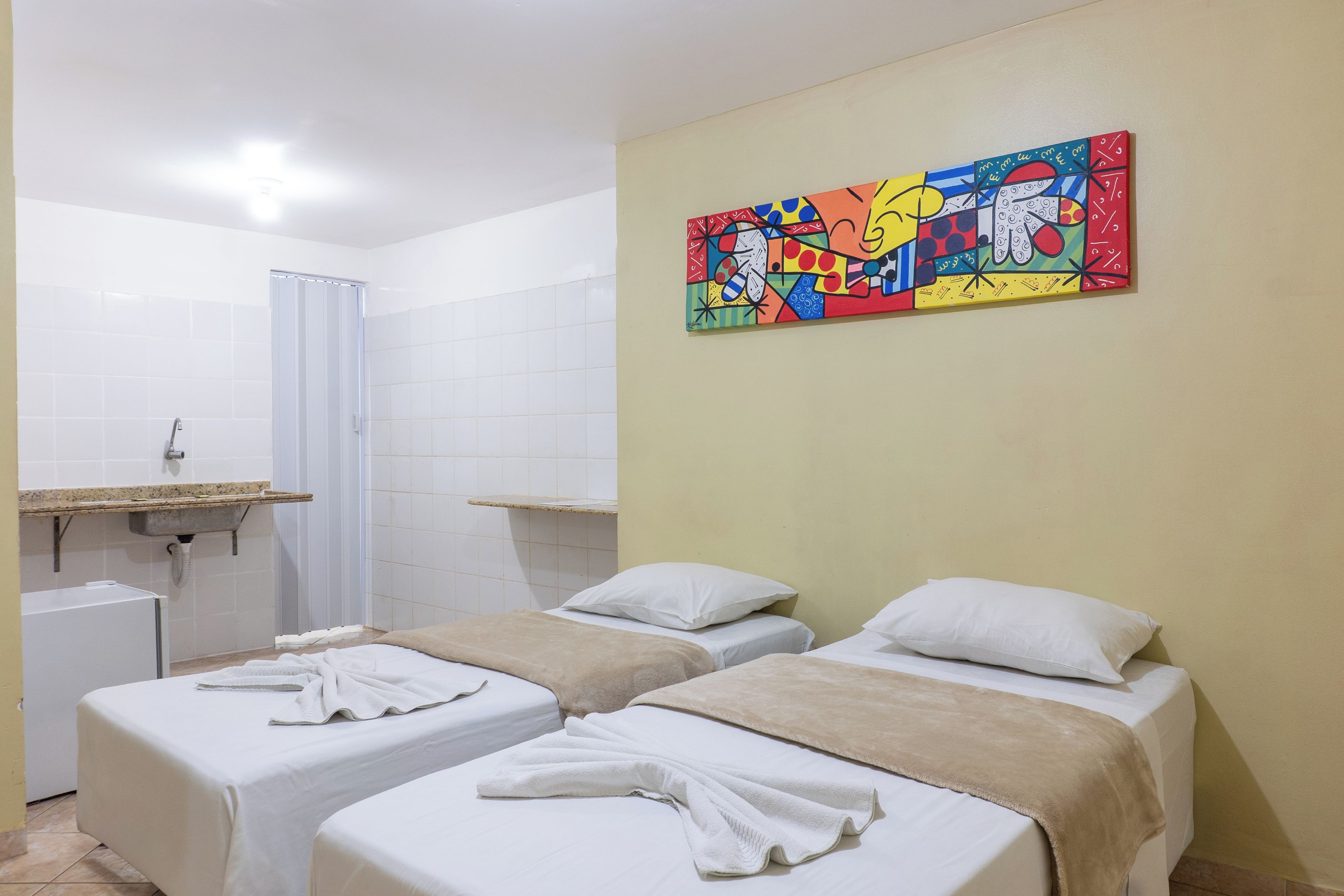 Una habitación de hotel con dos camas, ducha y lavamanos.