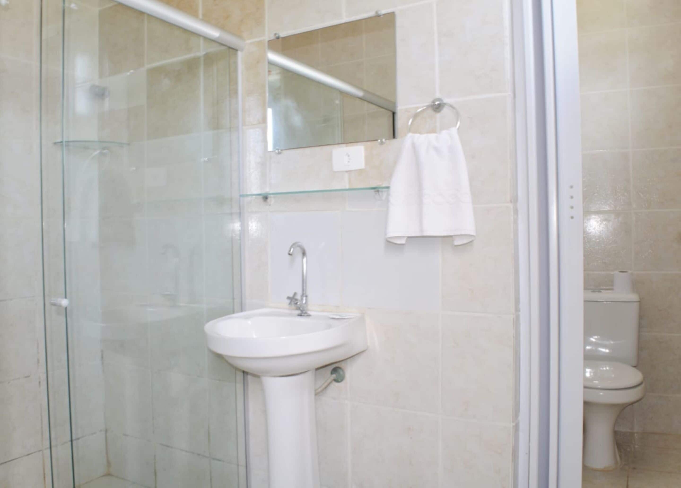 A bathroom with a glass shower enclosure, a white sink, and a toilet.