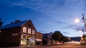Une vue d’une rue au crépuscule, avec des bâtiments, dont un immeuble en briques portant une enseigne indiquant « Dodge City Cyclists » et un magasin appelé « DCC ».