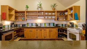 Une cuisine avec des meubles de rangement en bois, une cuisinière et divers ustensiles de cuisine.