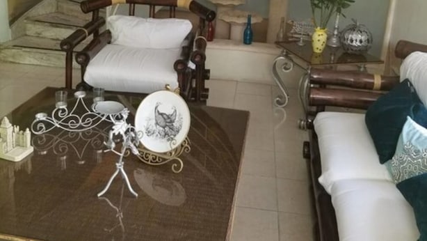 A cozy living room with a curved staircase, a coffee table with decorative items, and a mural on the wall. - Green House Aparta Hotel (Santo Domingo)