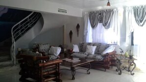 A living room with a sofa, armchairs, a coffee table, and a staircase. - Green House Aparta Hotel (Santo Domingo)