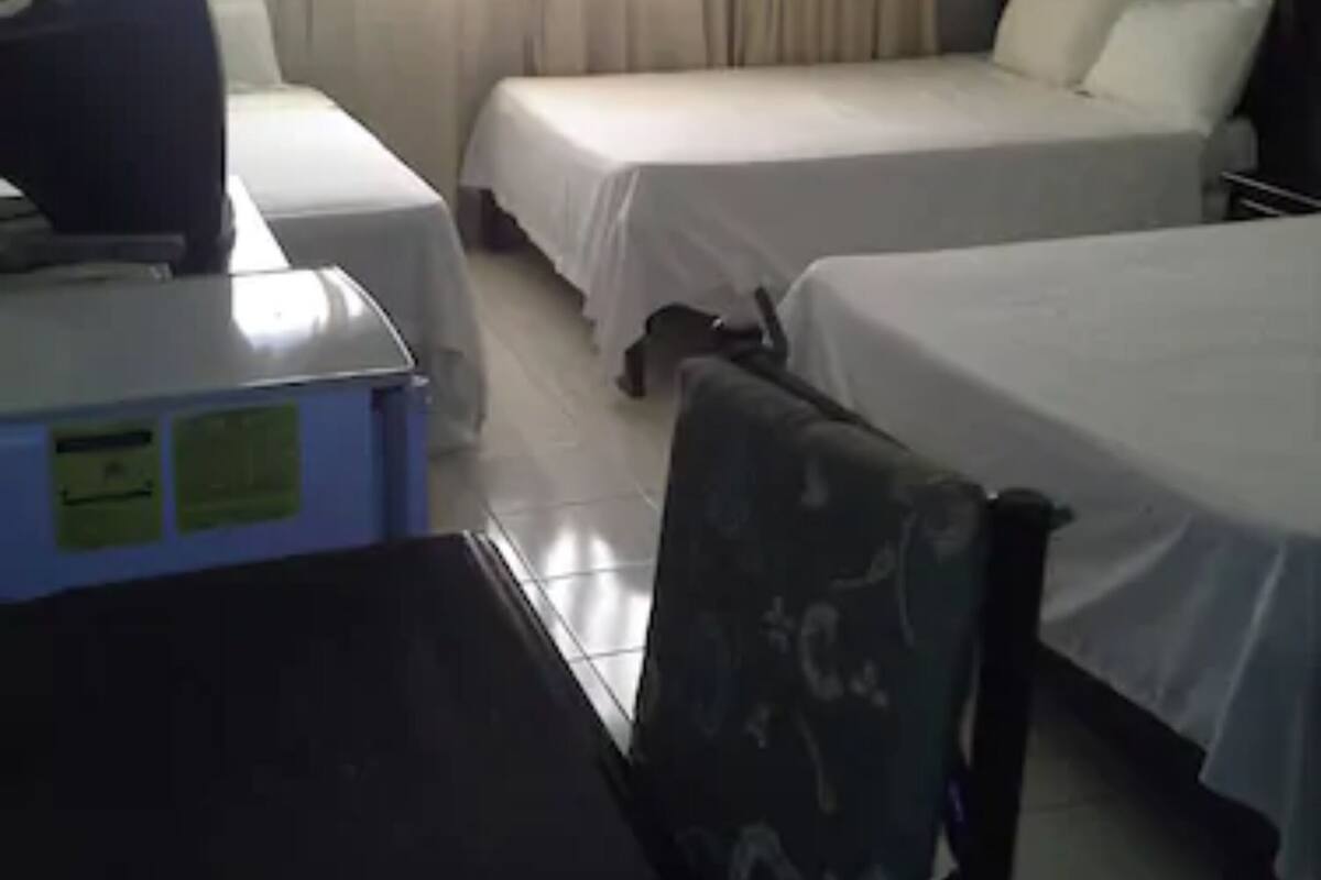 Une chambre d’hôtel avec deux lits, un bureau et une chaise.