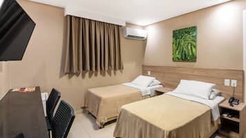 Habitación de hotel con dos camas, un escritorio con silla, aire acondicionado, un cuadro en la pared y un teléfono en la mesita de noche.