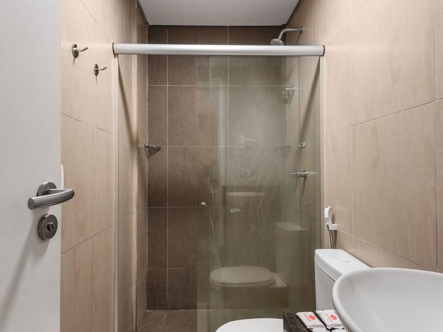 Un baño moderno con ducha de vidrio, inodoro y lavamanos amplio.