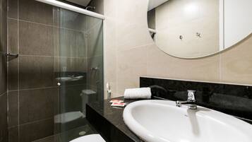 A modern bathroom with a glass-enclosed shower, a white sink, and a black countertop.