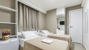 A hotel room with two beds, a minibar, a television, and a door. - VilaHotell Recife (Recife)