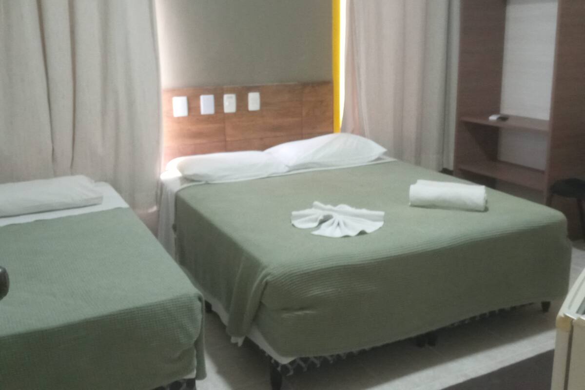 A hotel room with two single beds, a wooden headboard, a wardrobe, and a bedside table.
