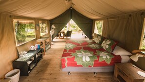 A tented accommodation with a bed, a table with chairs, and a view of the outdoors. - Ikurangi Eco Retreat (Rarotonga)