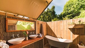 An outdoor bathroom with a wooden deck, two sinks, a freestanding bathtub, and a wooden fence. - Ikurangi Eco Retreat (Rarotonga)