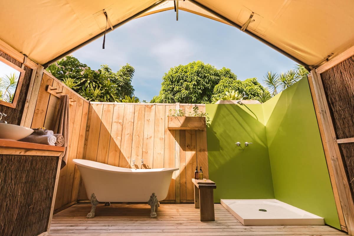 A wooden outdoor bathroom with a bathtub, shower, and wooden deck.