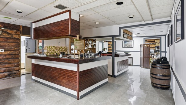 Uma área de recepção moderna com um balcão de madeira, um espelho grande e uma fonte decorativa.